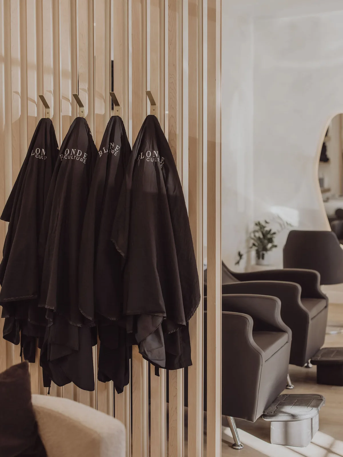 Blonde Culture capes hanging beside the shampoo chairs in Cochrane