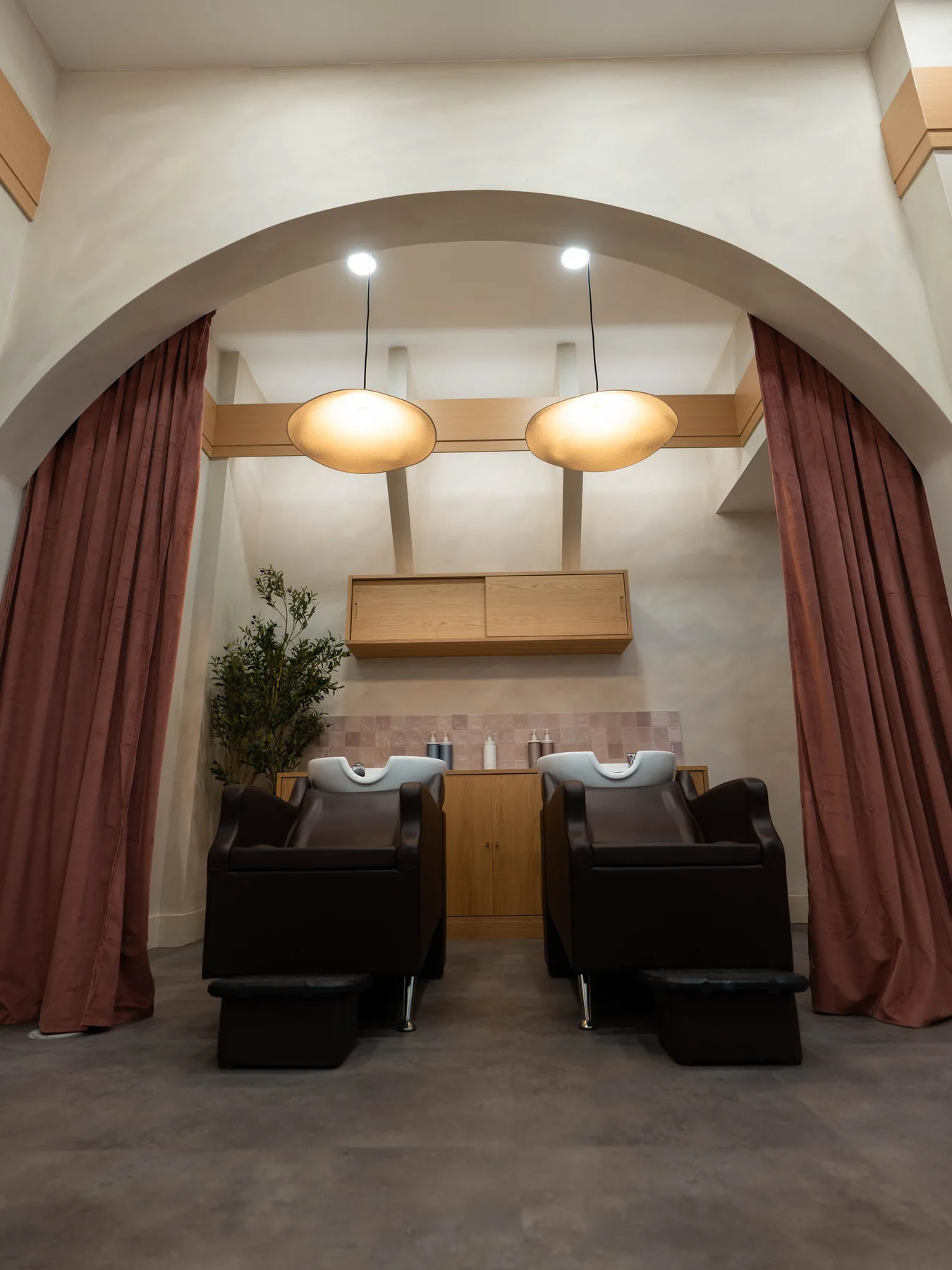 Shampoo area framed by an arch and rose curtains at Blonde Culture Winnipeg